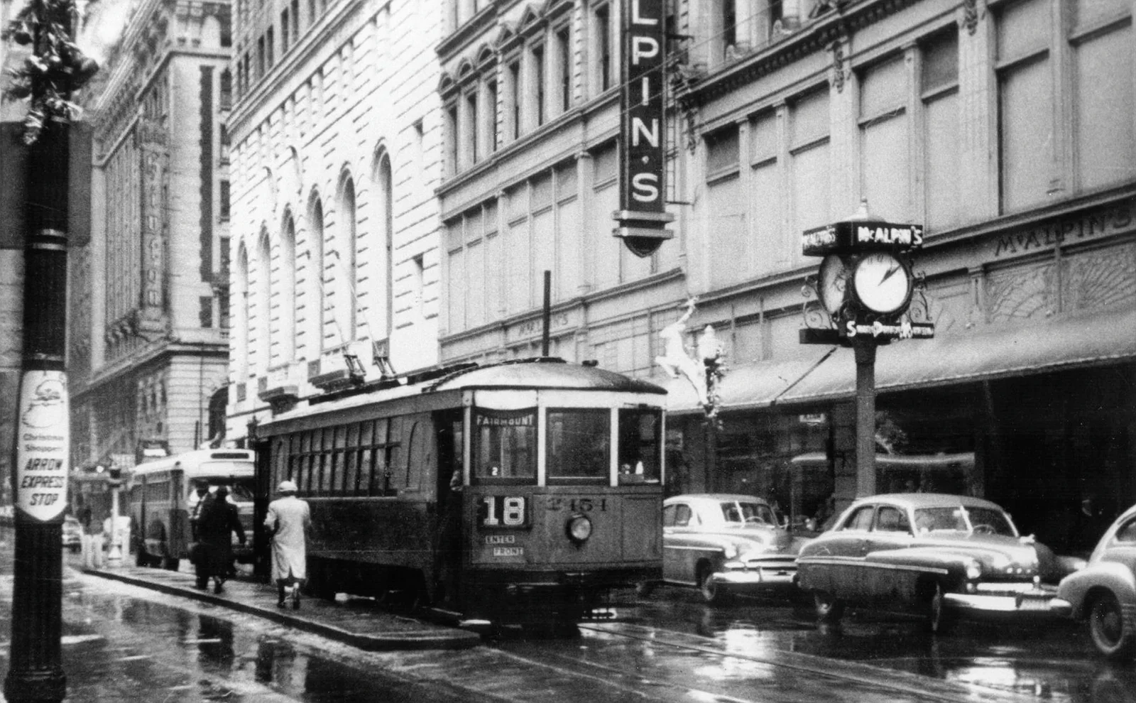 A black and white, atmospheric shot of Cincinnati streets, perhaps an old tram line or a notable building in the background